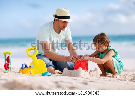Father and daughter on beach building sand castle