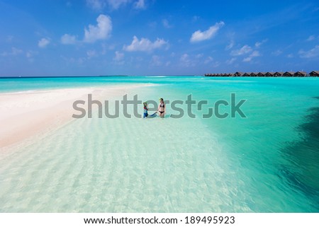 Above view of  mother and son walking at shallow turquoise ocean water with snorkeling equipment