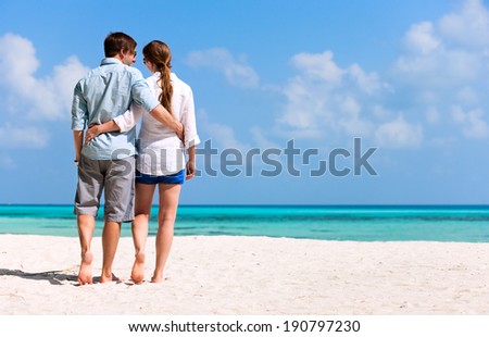 Back view of a romantic couple walking at beach during tropical vacation