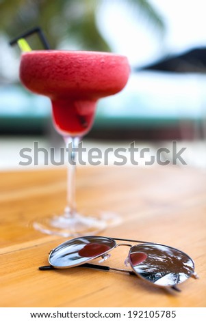 Tropical cocktail and sun glasses on a table at beach bar