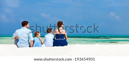 Back view of a beautiful family on a beach during summer vacation. Panorama perfect for banners