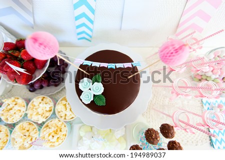 Berries, popcorn, canapes, candies and a chocolate cake on a dessert table at party