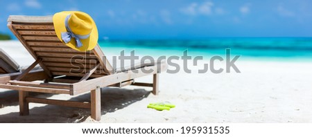 Yellow hat on a lounge chair at tropical beach panorama