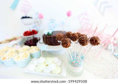 Berries, popcorn, canapes, candies, chocolate cake pops and a cake on a dessert table at party