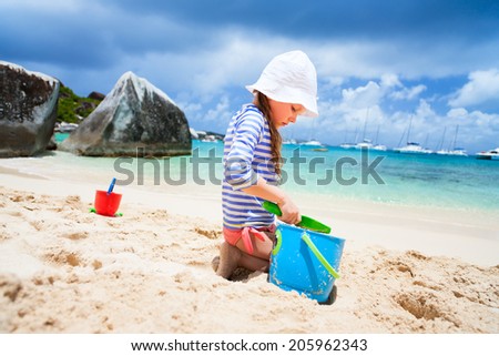Adorable little girl wearing rash guard for sun protection at beach during summer vacation
