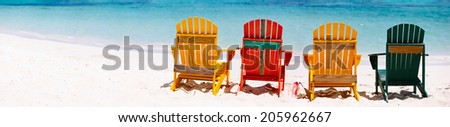 Row of colorful wooden chairs at tropical white sand beach in Caribbean, panorama with copy space perfect for banners