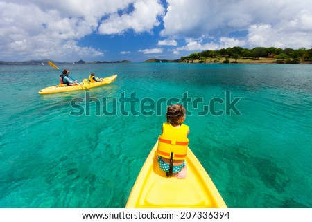 Family with kids paddling on colorful yellow kayaks at tropical ocean water during summer vacation