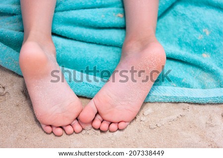Close up of a little girl feet on a beach towel