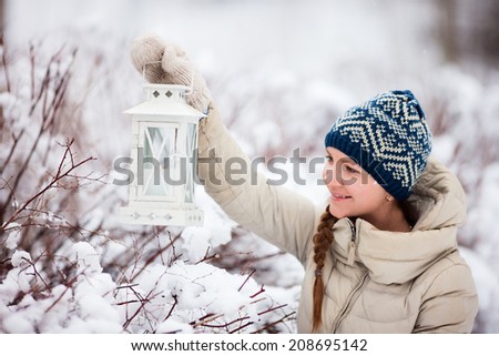 Young woman holding Christmas lantern outdoors on beautiful winter snow day