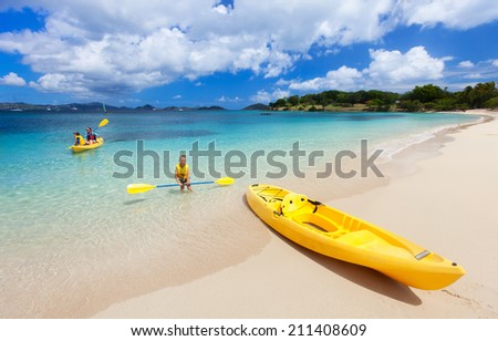 Family with kids paddling on colorful yellow kayaks at tropical ocean water during summer vacation