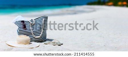 Straw hat, bag, sun glasses and flip flops on a tropical beach. Wide panorama, perfect for banners