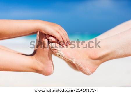 Close up of mother and daughter feet on a tropical sandy beach during vacation