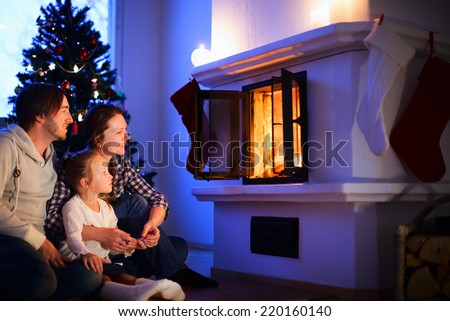 Family sitting by a fireplace in their family home on Christmas eve