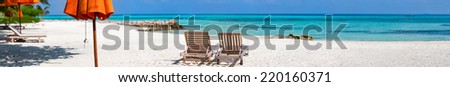 Panorama of a wooden lounge chairs on a beautiful tropical beach at Maldives