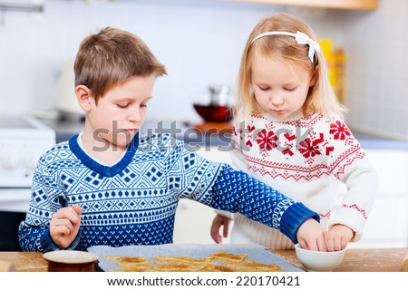 Kids wearing warm sweaters baking cookies in house kitchen on winter day