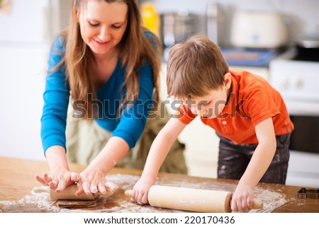 Young mother and her little son baking cookies together at home kitchen