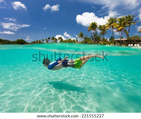Split of above and underwater photo of cute little boy swimming in ocean