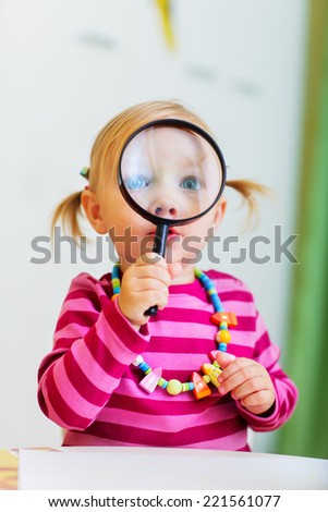 Adorable toddler girl looking through magnifier, perfect for early education context