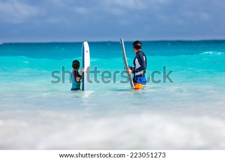 Father and son in ocean with boogie boards waiting for a wave