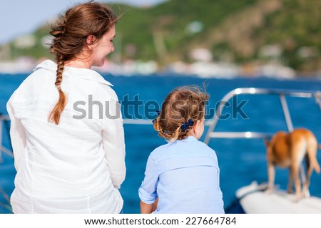 Back view of mother, daughter and their pet dog sailing on a luxury yacht or catamaran boat