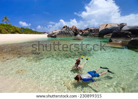 Family of young mother and son snorkeling in turquoise tropical water among huge granite boulders at beautiful tropical beach on Virgin Gorda,British Virgin Islands,Caribbean