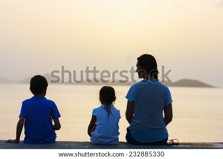 Back view family silhouettes on tropical coast at sunset