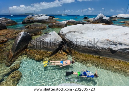 Family of young mother and son snorkeling in turquoise tropical water among huge granite boulders at The Baths beach area major tourist attraction on Virgin Gorda, British Virgin Islands, Caribbean