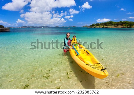Family of mother and son on colorful yellow kayak at tropical beach during summer vacation