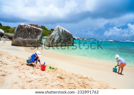Kids wearing sun protection rash guard playing at beach during summer vacation
