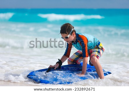 Little boy on vacation having fun surfing on boogie board