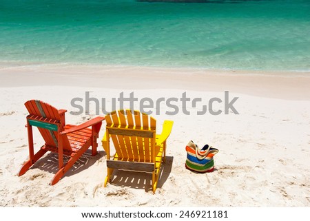 Colorful yellow and orange lounge chairs at tropical beach in Caribbean with beautiful turquoise ocean water and white sand