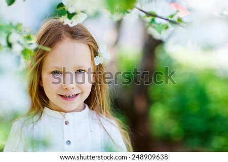 Adorable little girl in in blooming apple tree garden on spring day