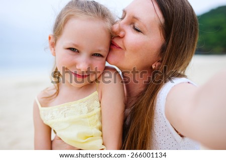 Happy family mother and her adorable little daughter at beach taking selfie