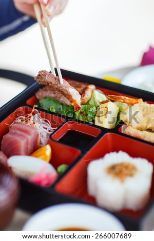 Delicious Japanese lunch bento box with rice, fish sashimi, omelet, meat and vegetables