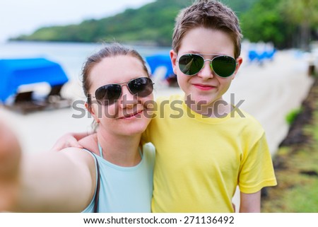 Happy family mother and son at beach taking selfie