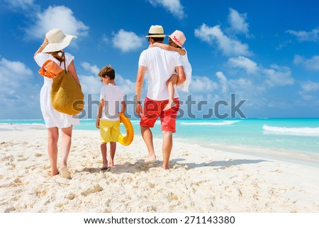 Back view of a happy family at tropical beach on summer vacation