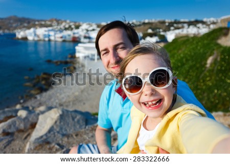 Happy family father and his adorable little daughter on vacation taking selfie at Little Venice area on Mykonos island, Greece
