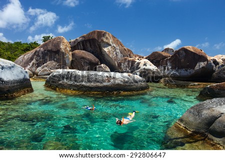 Family of mother and son snorkeling in turquoise tropical water among huge granite boulders at The Baths beach area major tourist attraction on Virgin Gorda, British Virgin Islands, Caribbean