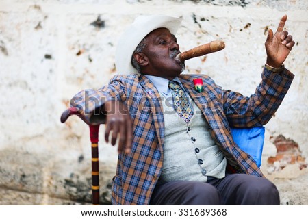 HAVANA, CUBA - JULY 17, 2013: Cuban man posing for photos while smoking big cuban cigar in Havana, Cuba.