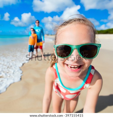 Little girl and her family father and brother enjoying beach vacation on Caribbean