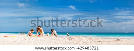 Mother and kids making sand castle at tropical beach