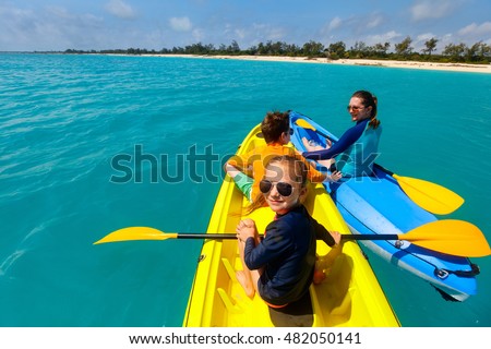 Family with kids paddling on colorful kayaks at tropical ocean water during summer vacation