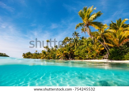 Stunning tropical island with palm trees, white sand, turquoise ocean water and blue sky at Cook Islands, South Pacific