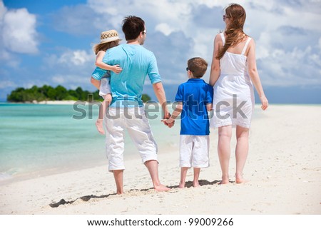 Back view of family with two kids on tropical beach
