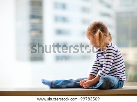 Adorable little girl sitting by the window