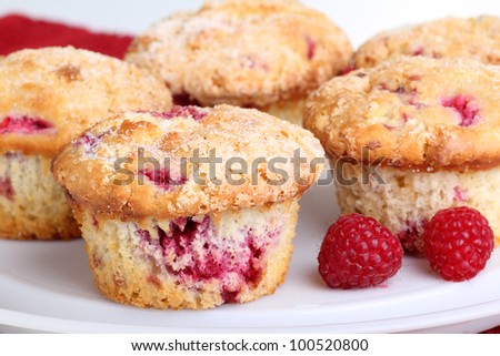 Several whole cranberry muffins and raspberry fruit on a platter