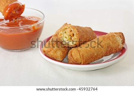 Egg rolls on a plate with dipping sauce on a table cloth