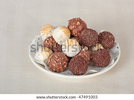 Plate of chocolate bon bon candy on a white table cloth Dark and white chocolate bon bon candy on a plate with a white table cloth background