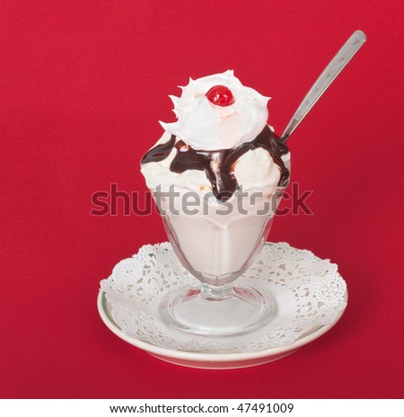 Ice cream sundae with whipped cream and cherry on a red background