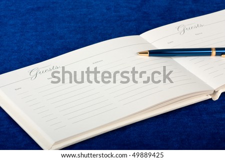 Opened wedding guest book with a pen on a blue background